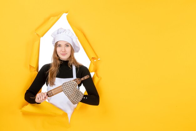 Cuoca vista frontale che tiene mattarello sulla foto gialla cucina lavoro colori cucina cibo sole