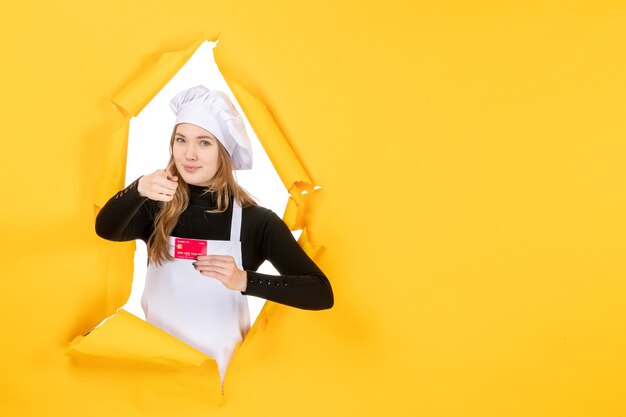 Cuoca vista frontale con carta di credito rossa su foto gialla emozione cibo cucina cucina colore denaro lavoro