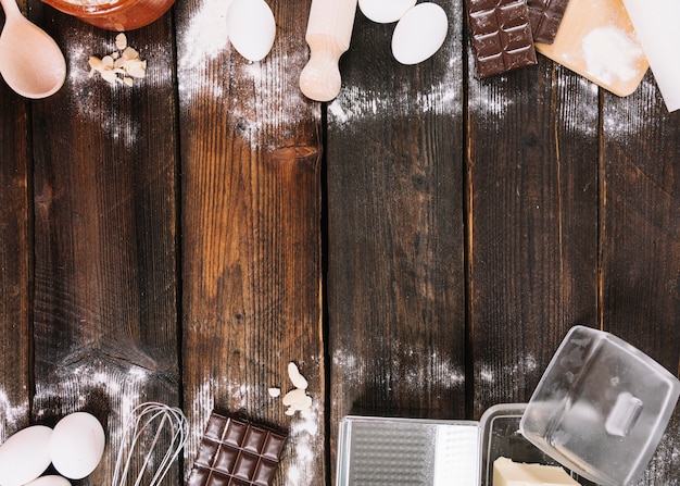 Cuocere gli ingredienti di una torta con utensili da cucina sul tavolo in legno