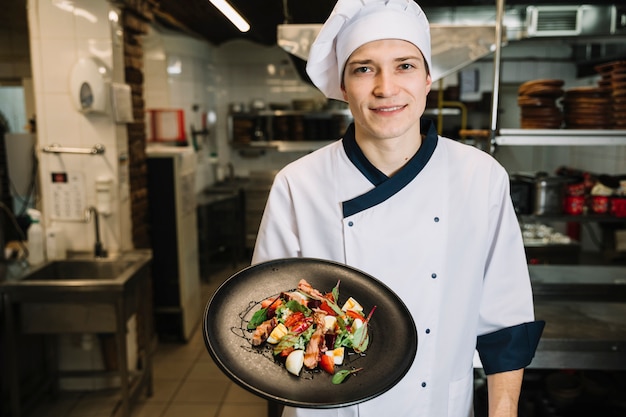 Cuocere mostrando insalata con carne sul piatto