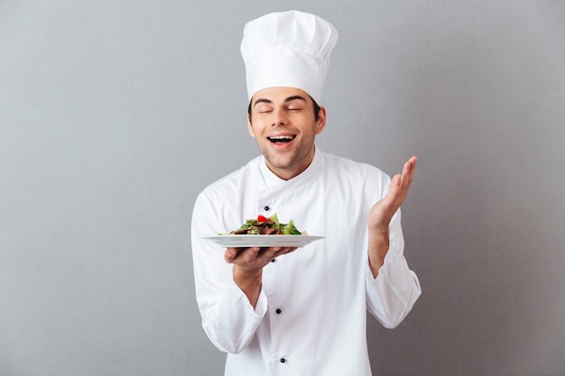 Cuoco bello giovane in insalata di odore uniforme