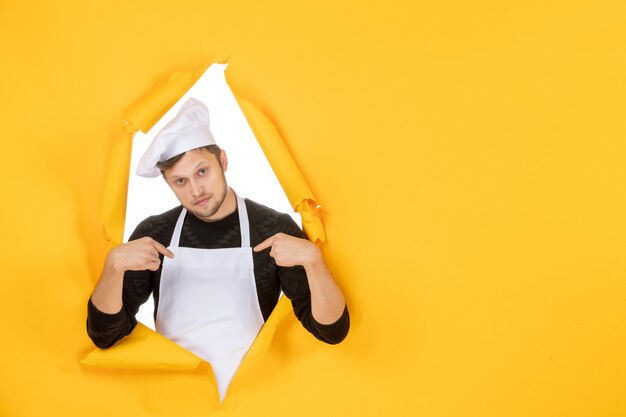 Cuoco maschio di vista frontale in mantello bianco e berretto su cibo strappato giallo lavoro cucina uomo cucina foto di colore