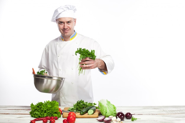 Cuoco unico che cucina l'insalata della verdura fresca nella sua cucina