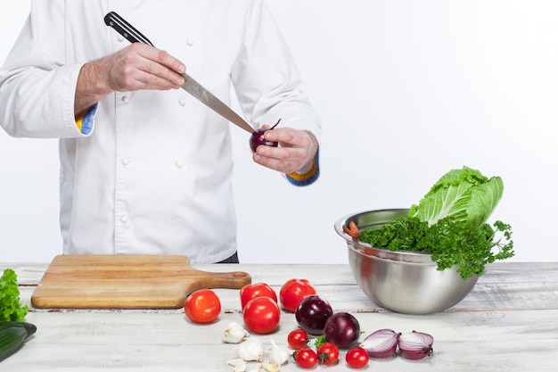 Cuoco unico che cucina l'insalata della verdura fresca nella sua cucina