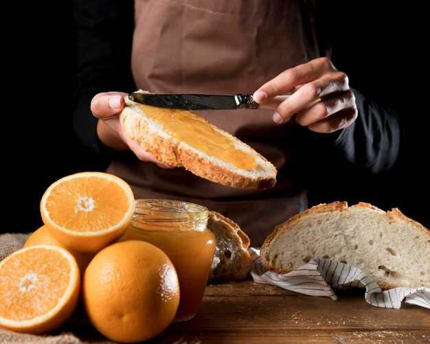 Cuoco unico che spande la marmellata di arance su pane