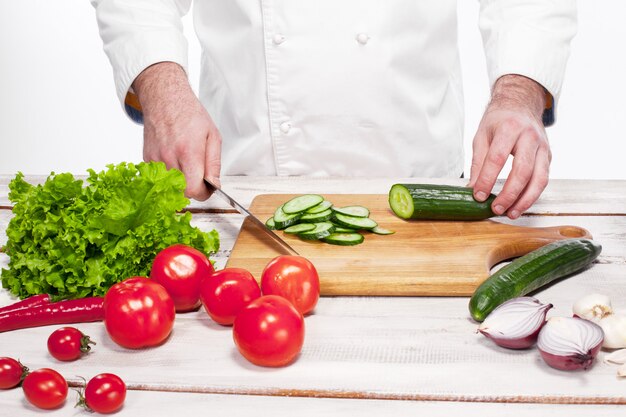 Cuoco unico che taglia un cetriolo verde nella sua cucina