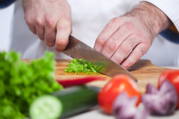 Cuoco unico che taglia una lattuga verde la sua cucina