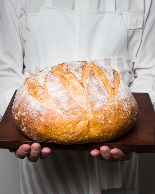 Cuoco unico che tiene delizioso pane rotondo