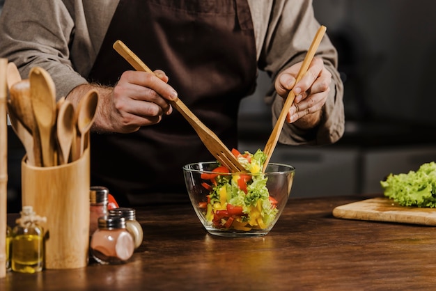 Cuoco unico del colpo metà che mescola gli ingredienti dell'insalata