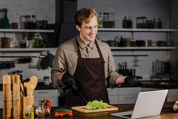 Cuoco unico del colpo metà con insalata che esamina computer portatile