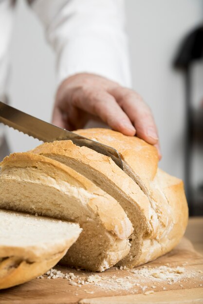 Cuoco unico del primo piano che affetta pane