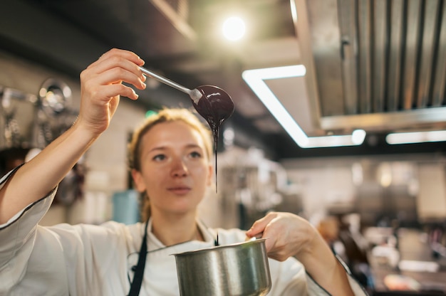 Cuoco unico femminile che controlla salsa