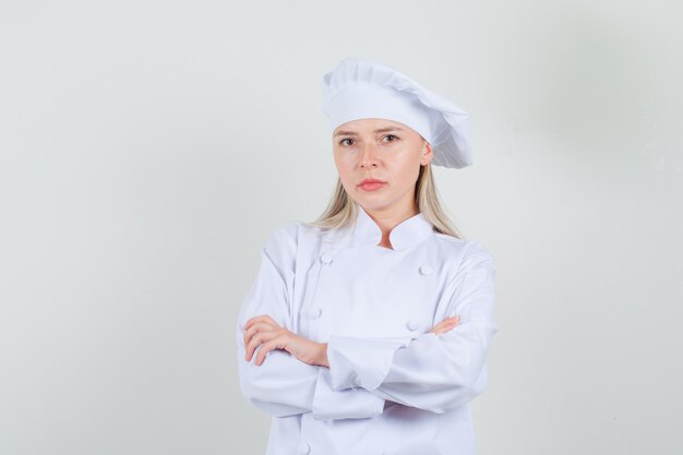 Cuoco unico femminile che guarda l'obbiettivo con le braccia incrociate in uniforme bianca e che sembra serio. vista frontale.