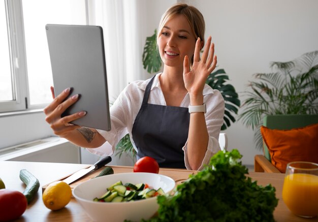 Cuoco unico femminile che ha una videochiamata mentre cucina