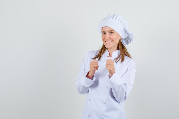 Cuoco unico femminile che mostra il gesto del vincitore in uniforme bianca e che sembra felice