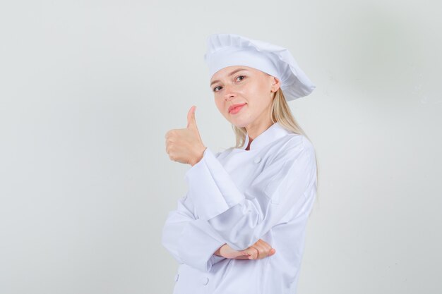 Cuoco unico femminile che mostra pollice in su in uniforme bianca e che sembra allegro.