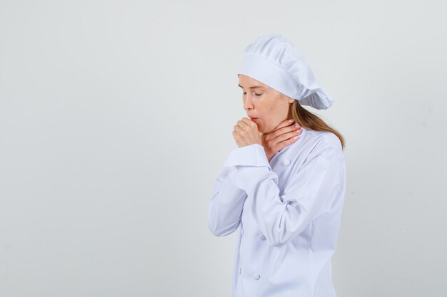 Cuoco unico femminile che soffre di tosse in uniforme bianca e sembra malato. .