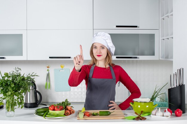 Cuoco unico femminile di vista frontale in cappello del cuoco che mostra il dito del punto