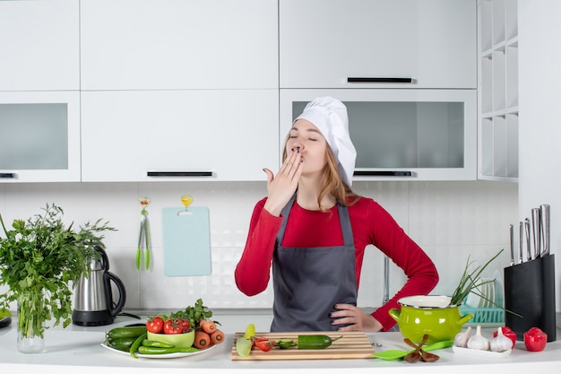 Cuoco unico femminile di vista frontale in cappello del cuoco che soffia bacio in cucina