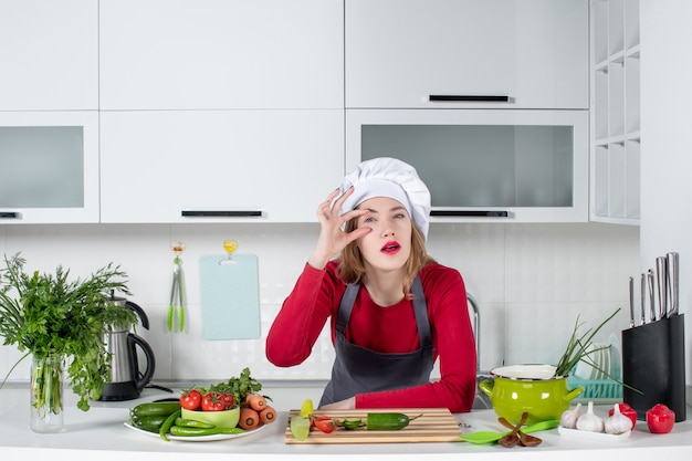 Cuoco unico femminile di vista frontale in cappello del cuoco che sta nella cucina