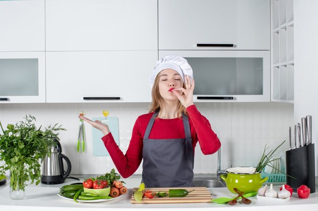 Cuoco unico femminile di vista frontale in grembiule che fa gesto di bacio dello chef