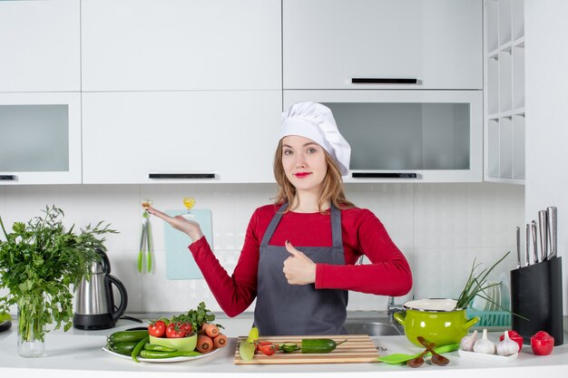 Cuoco unico femminile di vista frontale in grembiule che fa il segno di pollice in alto