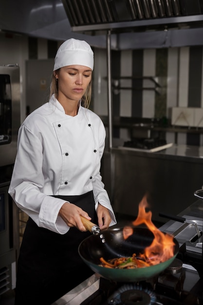 Cuoco unico femminile in cucina cibo fiammeggiante