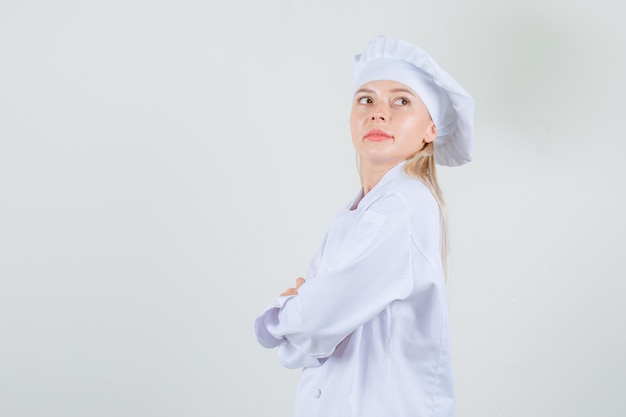 Cuoco unico femminile in uniforme bianca che guarda indietro con le braccia incrociate.