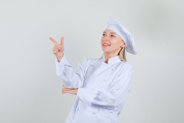 Cuoco unico femminile in uniforme bianca che mostra il gesto della pistola e che sembra allegro