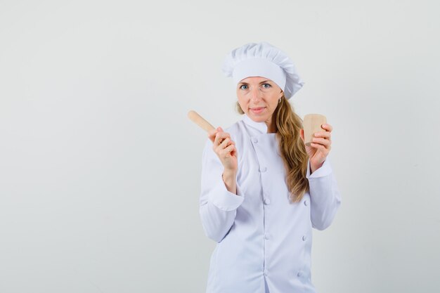 Cuoco unico femminile in uniforme bianca che tiene mortaio e pestello e sembra allegro
