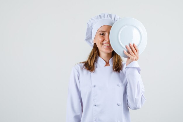 Cuoco unico femminile in zolla bianca della tenuta uniforme vicino al fronte e che sembra felice