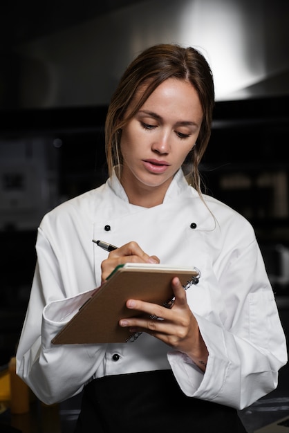 Cuoco unico in cucina a prendere appunti con penna e taccuino