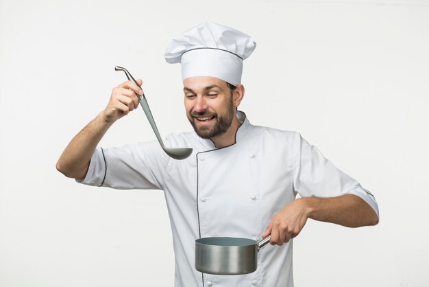 Cuoco unico maschio che assaggia zuppa in siviera contro fondo bianco