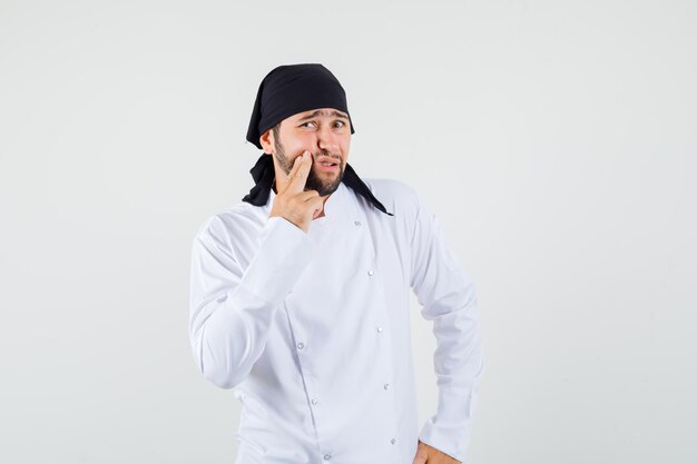 Cuoco unico maschio che ha un dente doloroso in uniforme bianca e sembra a disagio, vista frontale.