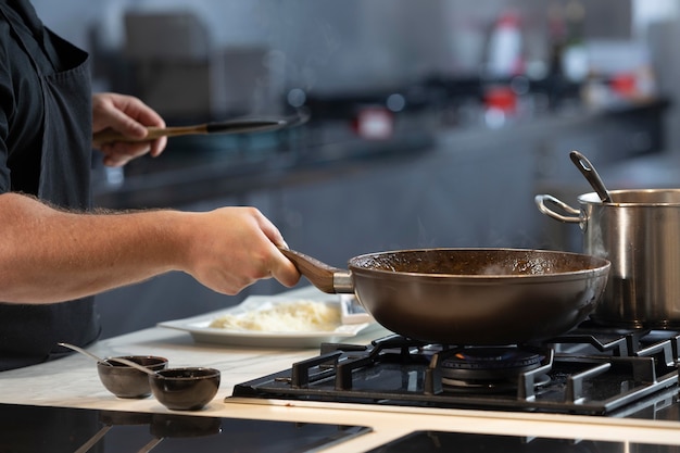 Cuoco unico maschio in cucina che cucina da vicino