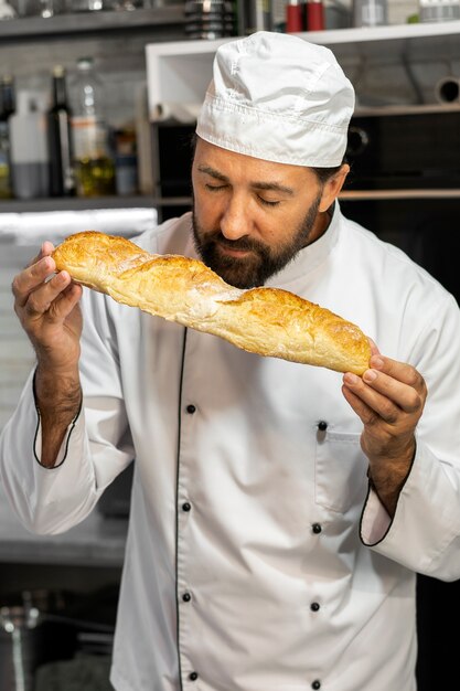 Cuoco unico maschio in cucina che sente l'odore del pane appena sfornato