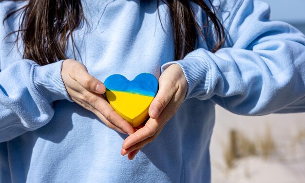 Cuore del primo piano nel colore della bandiera dell'ucraina in mani femminili