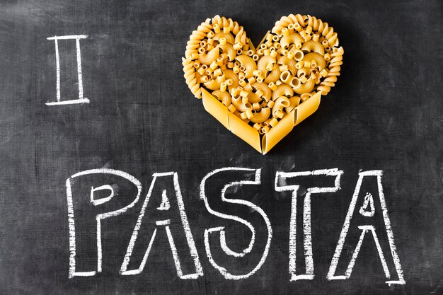 Cuore fatto con diversi tipi di pasta e testo sulla lavagna