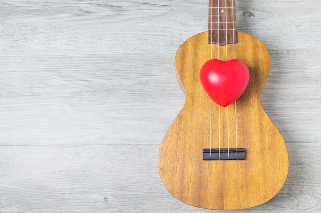 Cuore rosso sopra la chitarra di legno sopra la tavola di legno