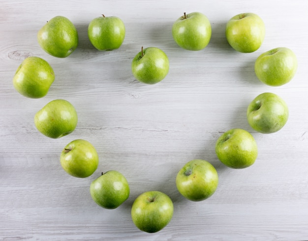 Cuore verde delle mele di vista superiore sull'orizzontale di legno bianco