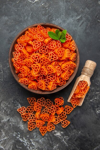 Cuori rossi di pasta italiana vista dall'alto in una ciotola cucchiaio di legno sul tavolo scuro