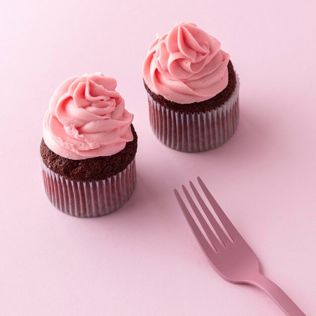 Cupcakes ad alto angolo con glassa rosa e forchetta