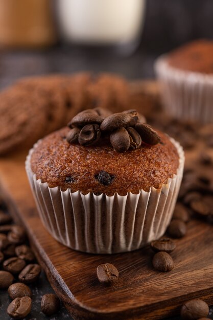 Cupcakes alla banana che vengono posizionati su un piatto di legno con chicchi di caffè.