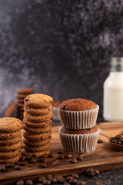 Cupcakes alla banana che vengono posizionati su un piatto di legno con chicchi di caffè.