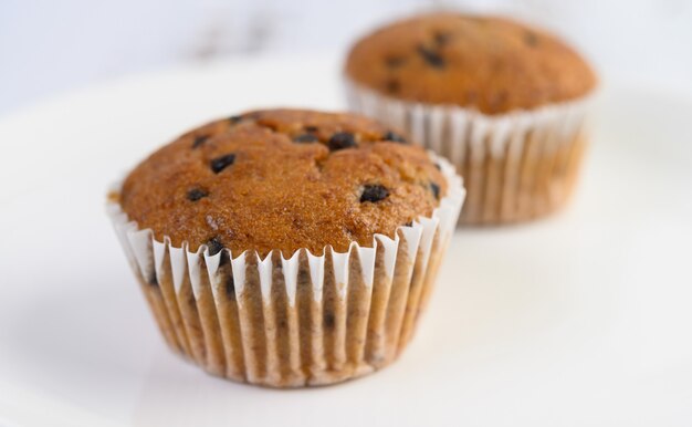 Cupcakes alla banana mescolati con gocce di cioccolato su un piatto bianco.