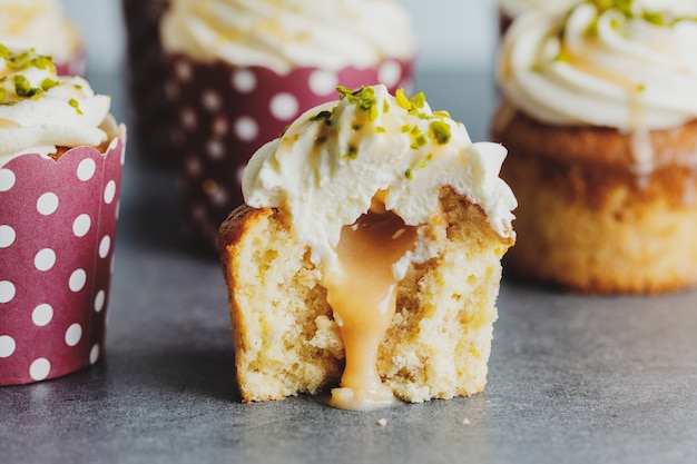 Cupcakes alla vaniglia con crema e caramello su sfondo grigio da tavola.