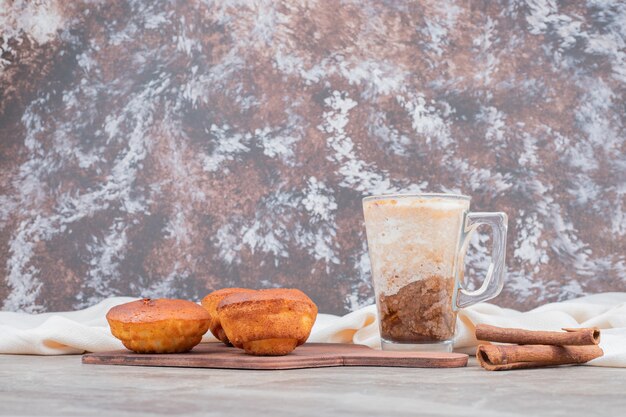 Cupcakes con un bicchiere di biscotti e cannella su tavola di legno.