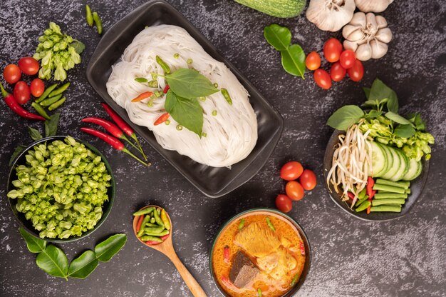 Curry di pollo in una tazza nera con spaghetti di riso.