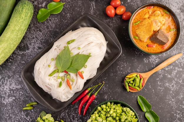 Curry di pollo in una tazza nera con spaghetti di riso.