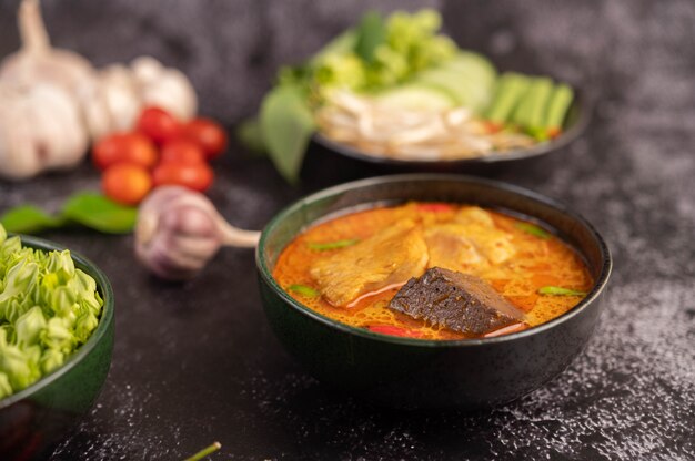 Curry di pollo in una tazza nera con spaghetti di riso.